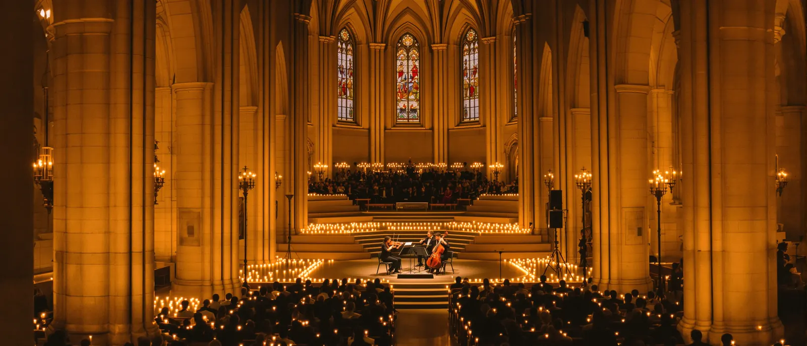 Candlelight-Konzert in einer gotischen Kirche: ein Streichquartett spielt, tausende Kerzen leuchten im Kirchenschiff